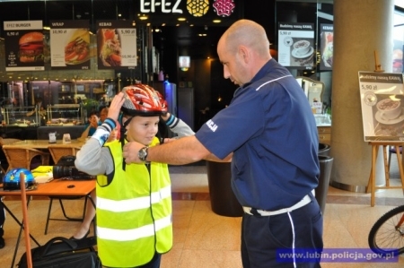 Policjant pomaga zapiąc kask młodemu rowerzyście, źródło: www.dolnoslaska.policja.gov.pl